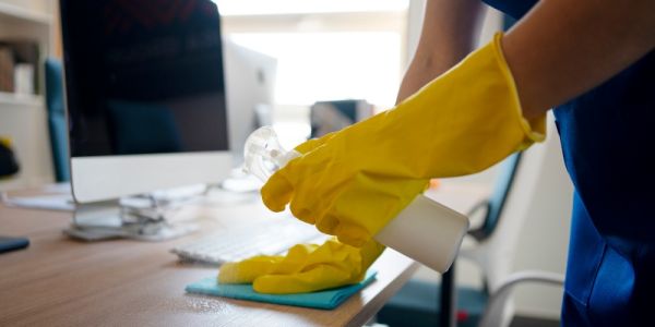 Profesional limpiando correctamente la mesa de una oficina
