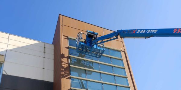 Profesional realizando trabajos de limpieza de cristales en altura con plataforma elevadora