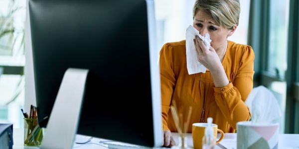 Trabajadora con síntomas de alergia por alérgenos ambientales en la oficina
